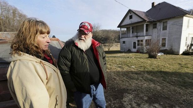 Julie and Phil Henneman, who lost their son Keith to suicide in 2006, when he was 29, talk about the experience outside the old farmhouse in Boscobel, Wisconsin. The devastating Midwest floods this spring increased concerns about the mental health and well-being of farmers who already were struggling with yearslong economic uncertainty.