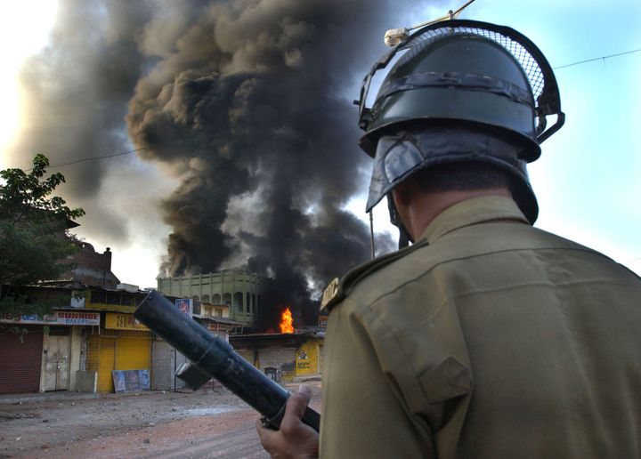 A police officer watches a Muslim-owned shop burning on March 1, 2002 in Ahmadabad.