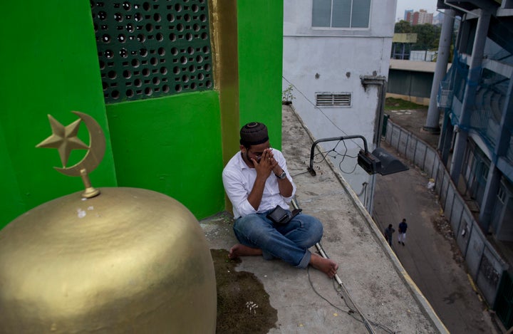 A Muslim volunteer prays perched on the roof of a mosque to spot possible hostile people during Friday prayers in Colombo, Sr