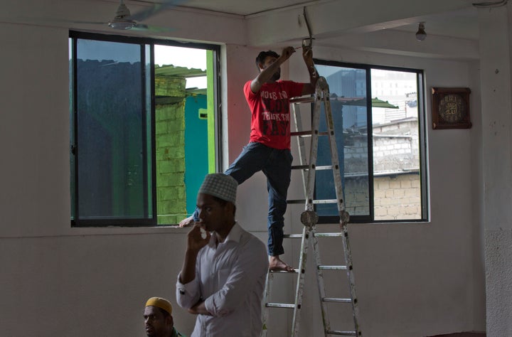 A man installs a close-circuit camera as men gather to pray at a mosque ahead of Friday prayers in Colombo, Sri Lanka, Friday, April 26, 2019. 