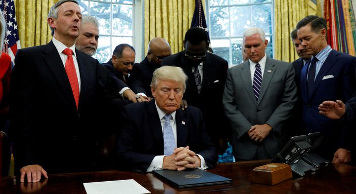 Faith leaders place their hands on the shoulders of President Donald Trump in the Oval Office as he takes part in a prayer on Sept. 1, 2017, for those affected by Hurricane Harvey.