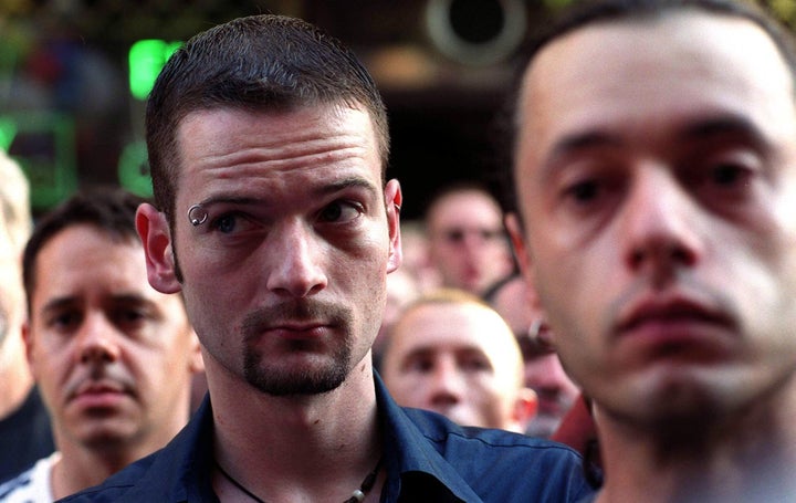 People stand for a one minute's silence outside the pub weeks after the attack.