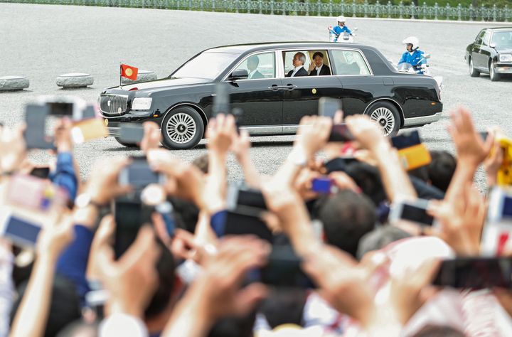 集まった人たちに手を振って皇居を出られる新天皇陛下＝１日午後、東京都千代田区