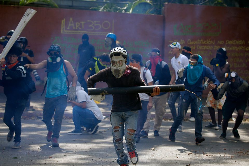 Anti-government protesters, one carrying a homemade mortar, take cover as security forces fire tear gas to disperse demonstrators in Caracas, Venezuela, Wednesday, May 1, 2019. Opposition leader Juan Guaidó called for Venezuelans to fill streets around the country Wednesday to demand President Nicolás Maduro's ouster. Maduro is also calling for his supporters to rally.  (AP Photo/Fernando Llano)