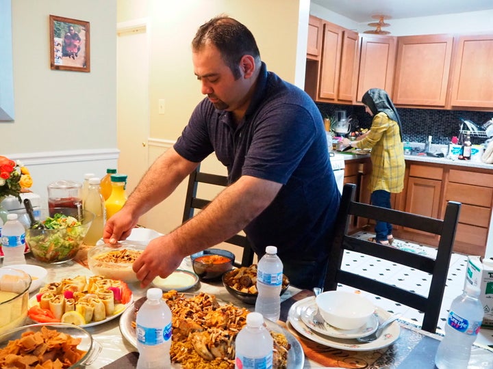 In this May 25, 2018, photo, Syrian refugee Majed Abdalraheem, 29, sets the table at his home in Riverdale, Md., as he and his wife, Walaa Jadallah, prepare for the Iftar meal during Ramadan. 