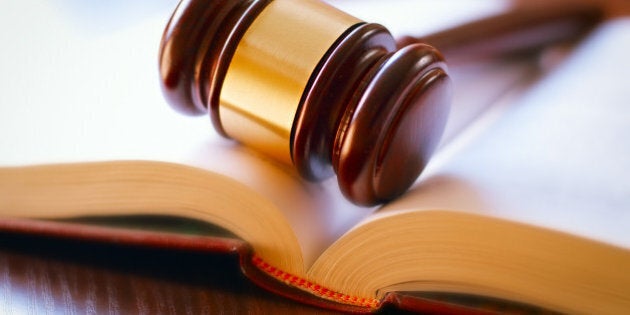 brown gavel and open book on a wooden table of the law in the courtroom