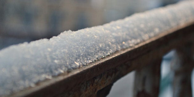 A snow cap on a metal railing of a balcony