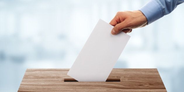 Ballot box with person casting vote on blank voting slip