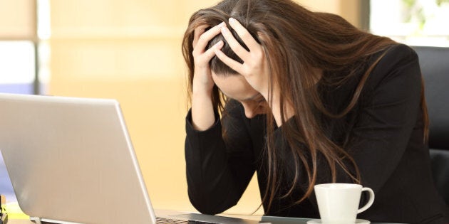 Desperate businesswoman on line worried after bankruptcy in front of a laptop with her hands in the head at office