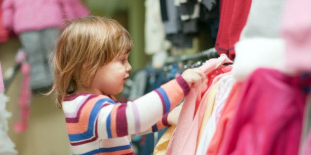 2 years baby girl chooses clothes at fashionable shop