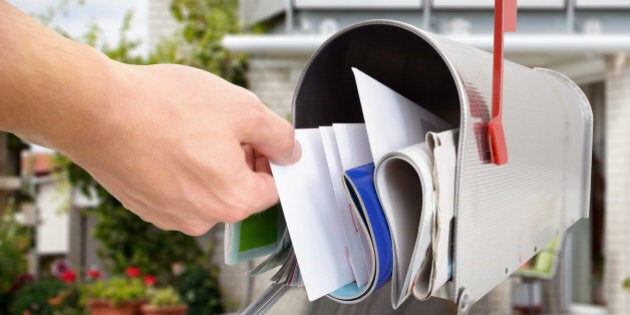 Close-up Of Man's Hand Taking Letter From Mailbox Outside House