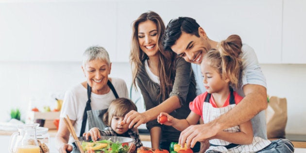 Three-generation family with two small children preparing food.