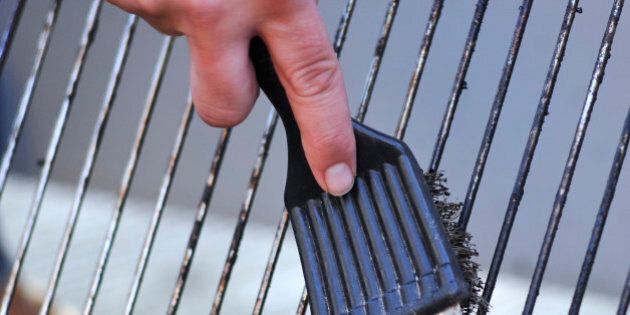human hand is cleaning the grill rost with scrubber