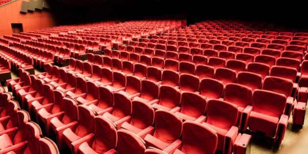 View from above into empty large Movie Theater - Auditorium. Large group of arranged Red Velvet Seats / Armchairs.