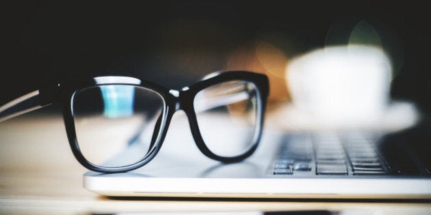 Glasses on laptop with pen, close up