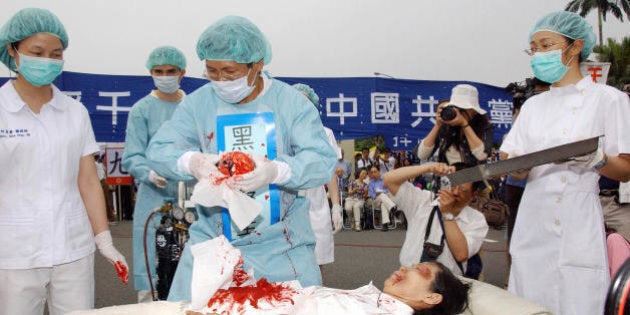 Taipei, TAIWAN: During a rally joined by thousands of Falun Gong practitiioners at Taipei 23 April 2006, four demonstrators play in an action drama against what they said was the Chinese communists' killing of Falun Gong followers and harvesting of their organs in concentration camps. China outlawed the Falun Gong, which combines meditation with Buddhist-inspired teachings, as an 'evil cult' in mid-1999 and practitioners have subsequently faced often brutal repression. AFP PHOTO/PATRICK LIN (Photo credit should read PATRICK LIN/AFP/Getty Images)