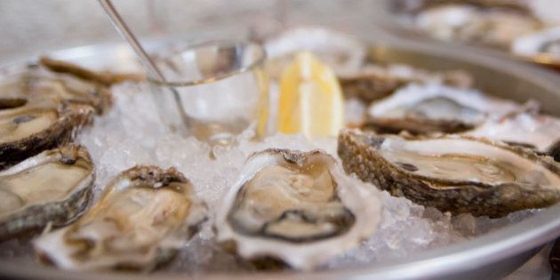 'Fresh oysters served with white wine. Delights of Cancale in Bretagne, a region of growing oysters. Selective focus on foreground, very short depth of field. Natural light.'