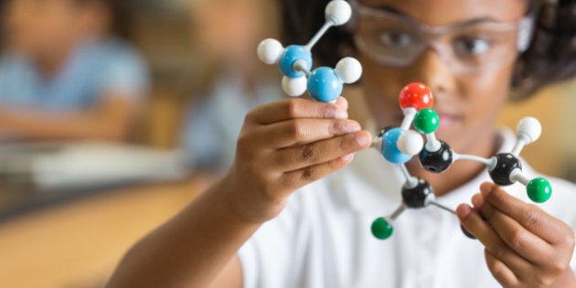 Elementary science student using plastic atom model educational toy