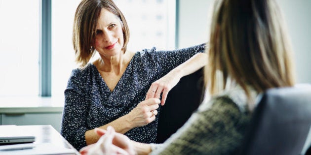 Mature businesswoman in discussion with female colleague at conference table in office