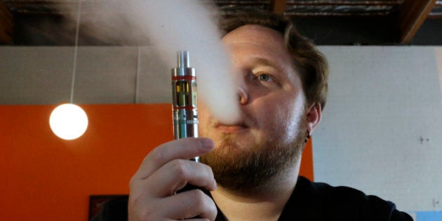 FILE - In this July 16, 2015 file photo, Bruce Schillin, 32, exhales vapor from an e-cigarette in Sacramento, Calif. In 2015, the rate of smoking among adults in the U.S. fell to 15 percent due to the biggest one-year decline in more than 20 years, according to a report by the Centers for Disease Control and Prevention released on Tuesday, May 24, 2016. The increased popularity of electronic cigarettes has likely played a role, but it is not yet clear whether this will help further propel the decline in smoking, or contribute to an increase in smoking in years to come. (AP Photo/Rich Pedroncelli, File)