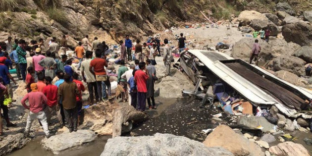 Indian rescue personnel and volunteers stand amidst wreckage and victims after a bus accident, at the bottom of a ravine near the River Tons at Chopal, some 115kms north of Shimla on April 19, 2017. A bus has swerved off a mountain road and plunged into a deep ravine in a Himalayan region of northern India, killing at least 44 people, an official said. The bus with 56 passengers on board plunged into a river in northern Himachal Pradesh state. / AFP PHOTO / STR (Photo credit should read STR/AFP/Getty Images)