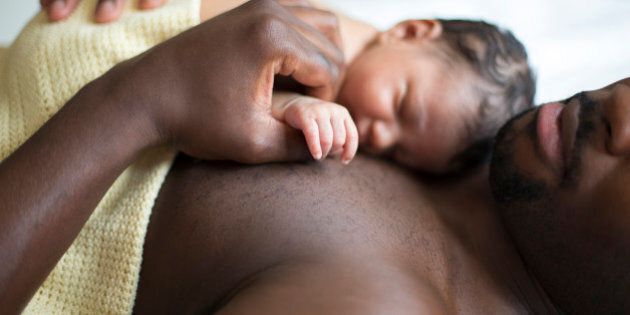 A father lying down with his newborn baby daughter sleeping on his chest.