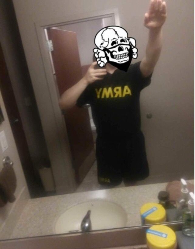 A photo posted to Corwyn Storm Carver's Tumblr page, showing him in Army shorts and T-shirt and throwing up a Nazi salute. His face is blocked by a skull-and-bones illustration often used by members of the Atomwaffen Division. (The photo was provided to HuffPost by journalist Nate Thayer.)