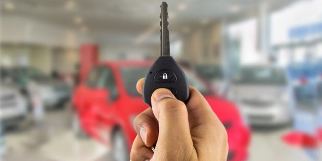 man holding a car key with remote in the concessionaire