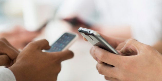 Close up of friends texting with cell phones at table