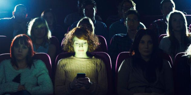 Woman using phone during movie at cinema