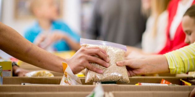 Young adults at a community service food bank, preparing boxes with food donations.
