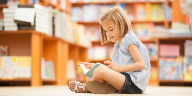 Girl sitting on floor of library with book