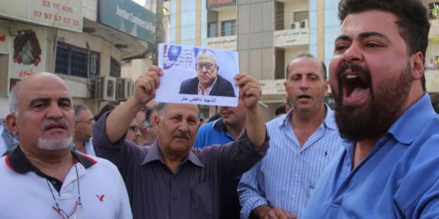Demonstrators shout slogans during a demonstration in the town of Fuheis, 20km northwest of the capital Amman on September 25, 2016, denouncing the killing of prominent Jordanian writer Nahed Hattar (portrait).Hattar was shot dead on the steps of a court where he was facing charges for sharing an anti-Islam cartoon online, in an attack condemned as 'heinous'.Nahed, a 56-year-old Christian, was struck by three bullets before the alleged assassin was arrested at the scene of the shooting in Amman's central Abdali district, said the official Petra news agency. / AFP / Khalil MAZRAAWI (Photo credit should read KHALIL MAZRAAWI/AFP/Getty Images)