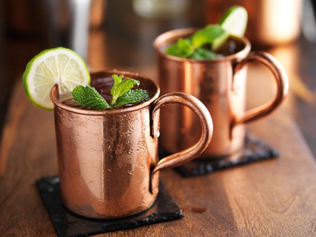 moscow mules in copper cups on slate coasters, garnished with mint and lime