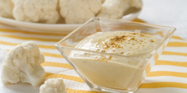 A bowl of dip with fresh cauliflower on background, selective focus