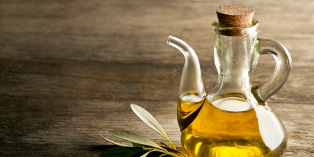 Olive oil and olive branch on the wooden table.