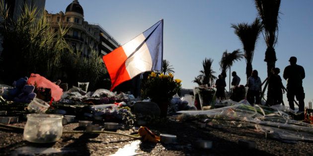 A French flag stands stall amongst a floral tribute for the victims killed during a deadly attack, on the famed Boulevard des Anglais in Nice, southern France, Sunday, July 17, 2016. French authorities detained two more people Sunday in the investigation into the Bastille Day truck attack on the Mediterranean city of Nice that killed at least 84 people, as authorities try to determine whether the slain attacker was a committed religious extremist or just a very angry man. (AP Photo/Laurent Cipriani)