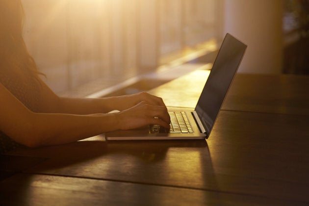 Woman typing as the sun sets behind her.