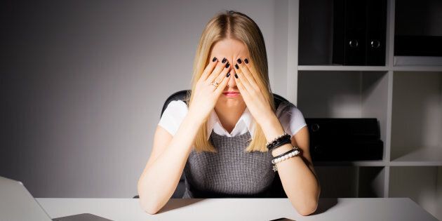 Woman sitting in her office with her eyes covered