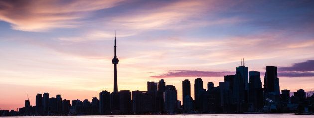 Family picnic at the shore of Toronto island with Toronto skyline at dusk on the background. Ontario. Canada.
