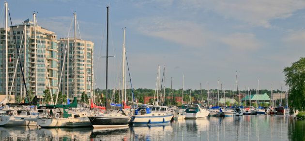 Barrie marina with condominium towers in the background. The sailboats or yachts are reflecting in the water.
