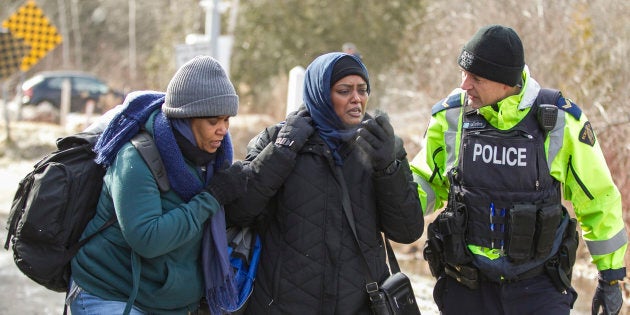 Un officier de la GRC parle avec des femmes originaires du Soudan après qu'elles aient traversé la frontière canado-américaine de manière irrégulière près de Hemmingford, au Québec, le 26 février 2017. (GEOFF ROBINS/AFP/Getty Images)