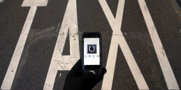 The logo of car-sharing service app Uber on a smartphone over a reserved lane for taxis in a street is seen in this photo illustration taken December 10, 2014. REUTERS/Sergio Perez/Illustration/Files