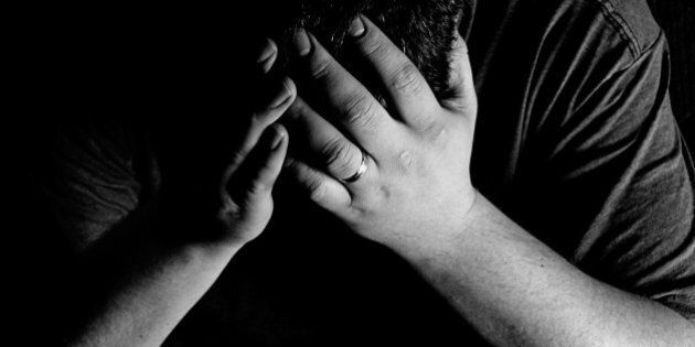 A man holds his head in his hands, in obvious grief.