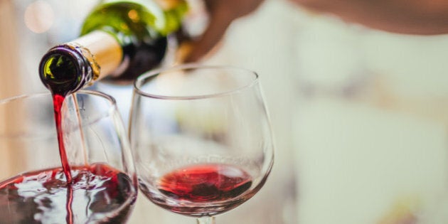 Unrecognizable man pouring red wine in two glasses.