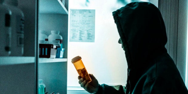 A young male drug addict stealing prescriptions off the shelf of a pharmacy.