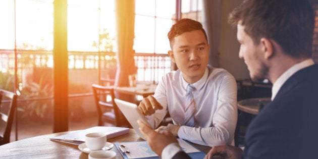 Two businessmen sitting in cafe and discussing business project