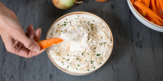 Homemade onion dip made with caramelized onion, sour cream, chives, and salt on a slate surface.