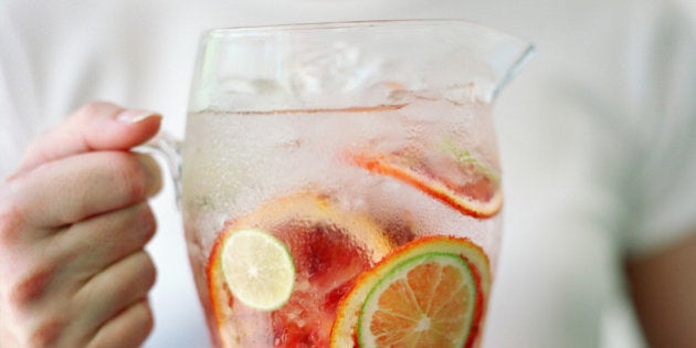 Woman holding pitcher of water with orange and lime slices