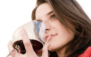 a beautiful woman smell a red glass wine
